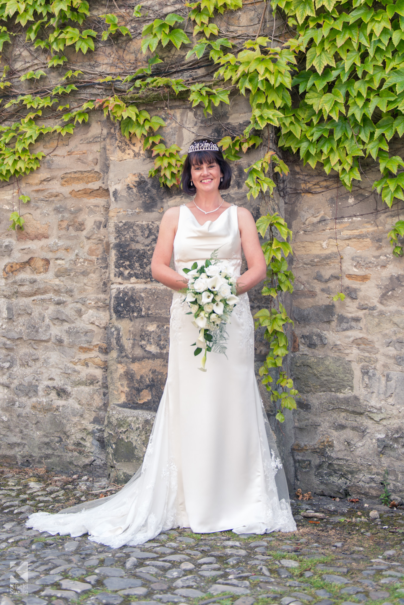 Bride standing next to ivy outside in her white dress