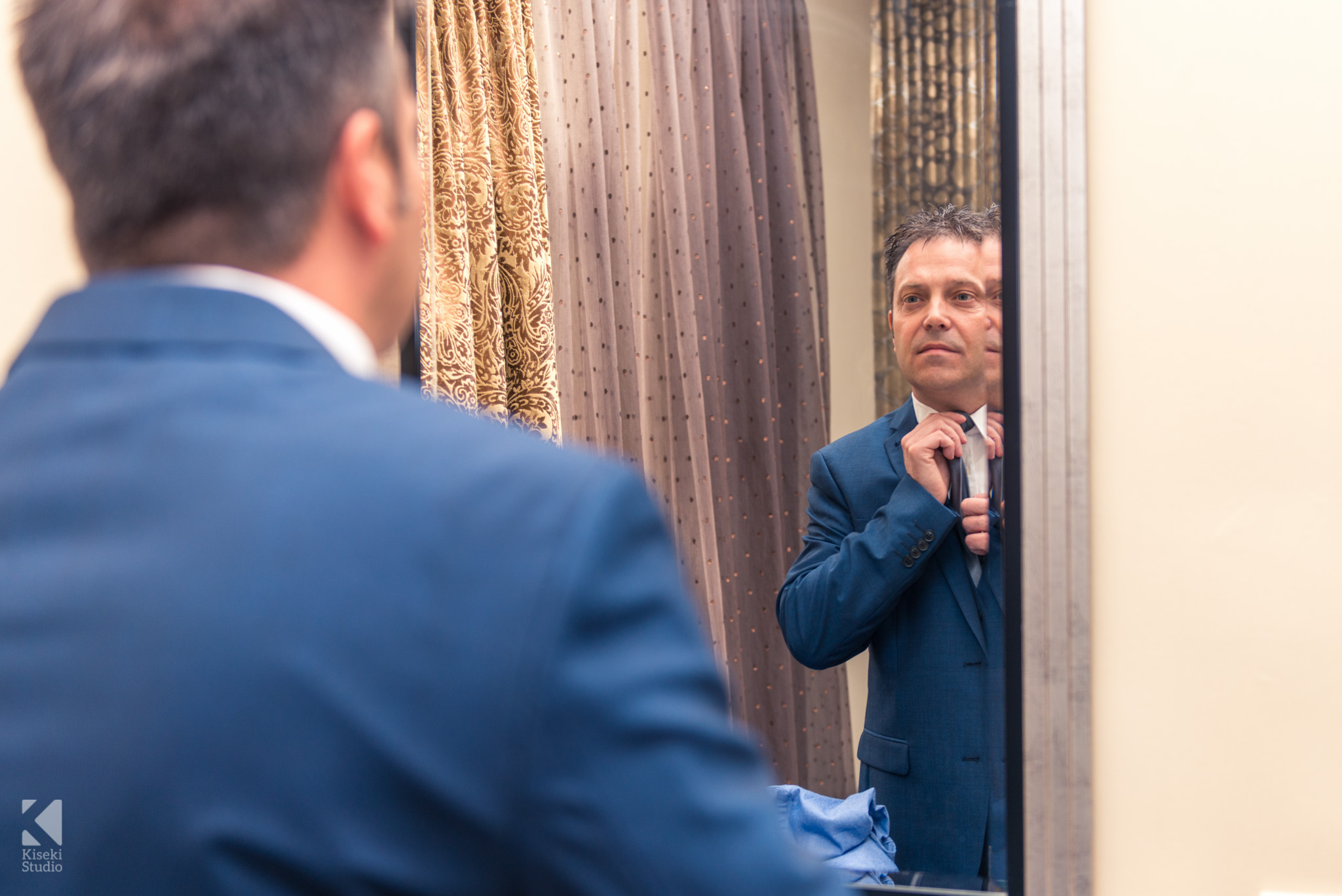 Groom fixing his tie before the wedding